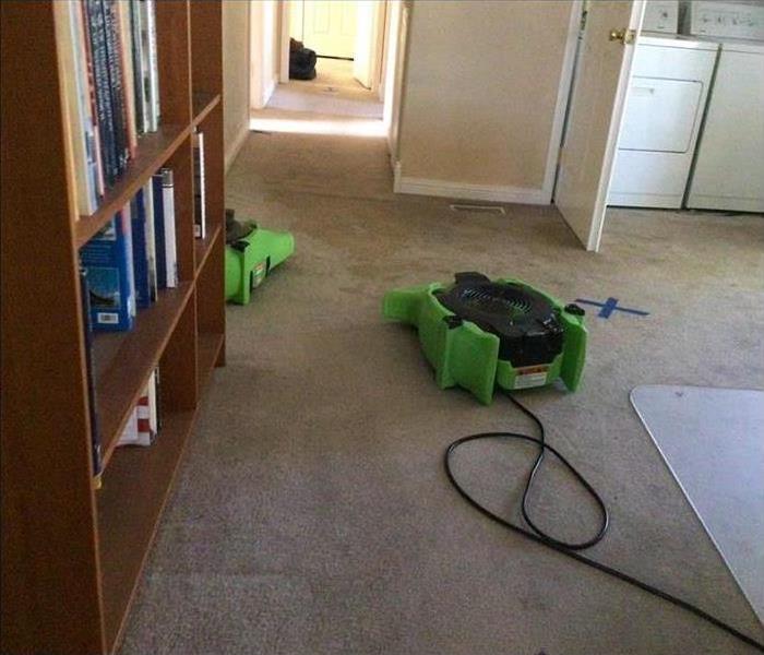 two air movers placed on carpet floor,  blue tape on floor use as signs